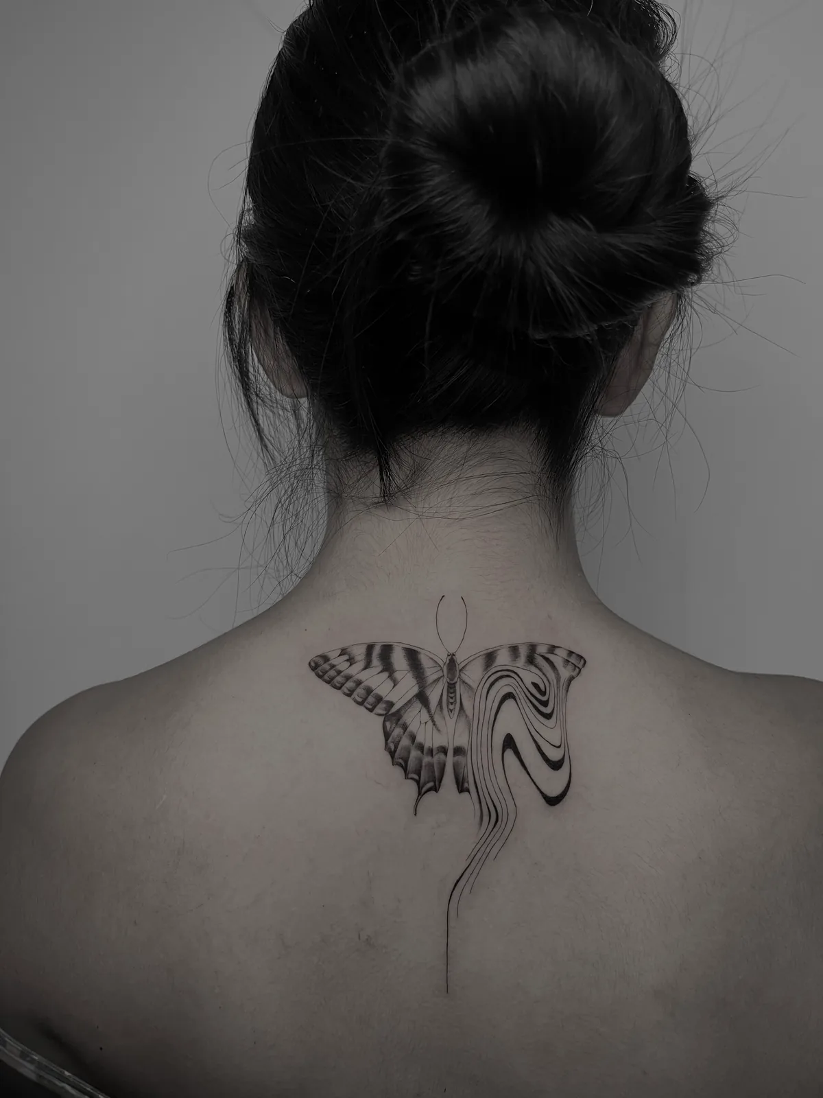 Liquid marbled blackwork butterfly across the upper back, GAR Tattoo