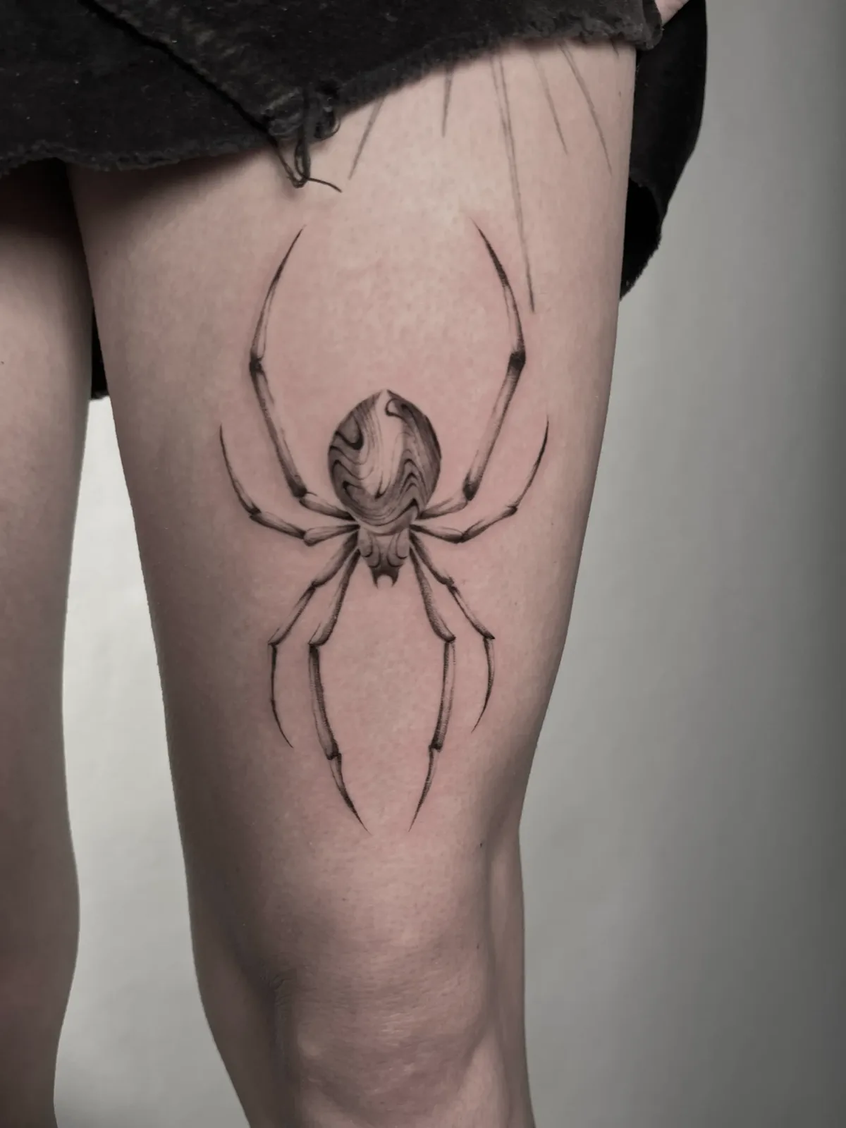 Illustrative blackwork spider tattoo on the thigh, GAR Tattoo