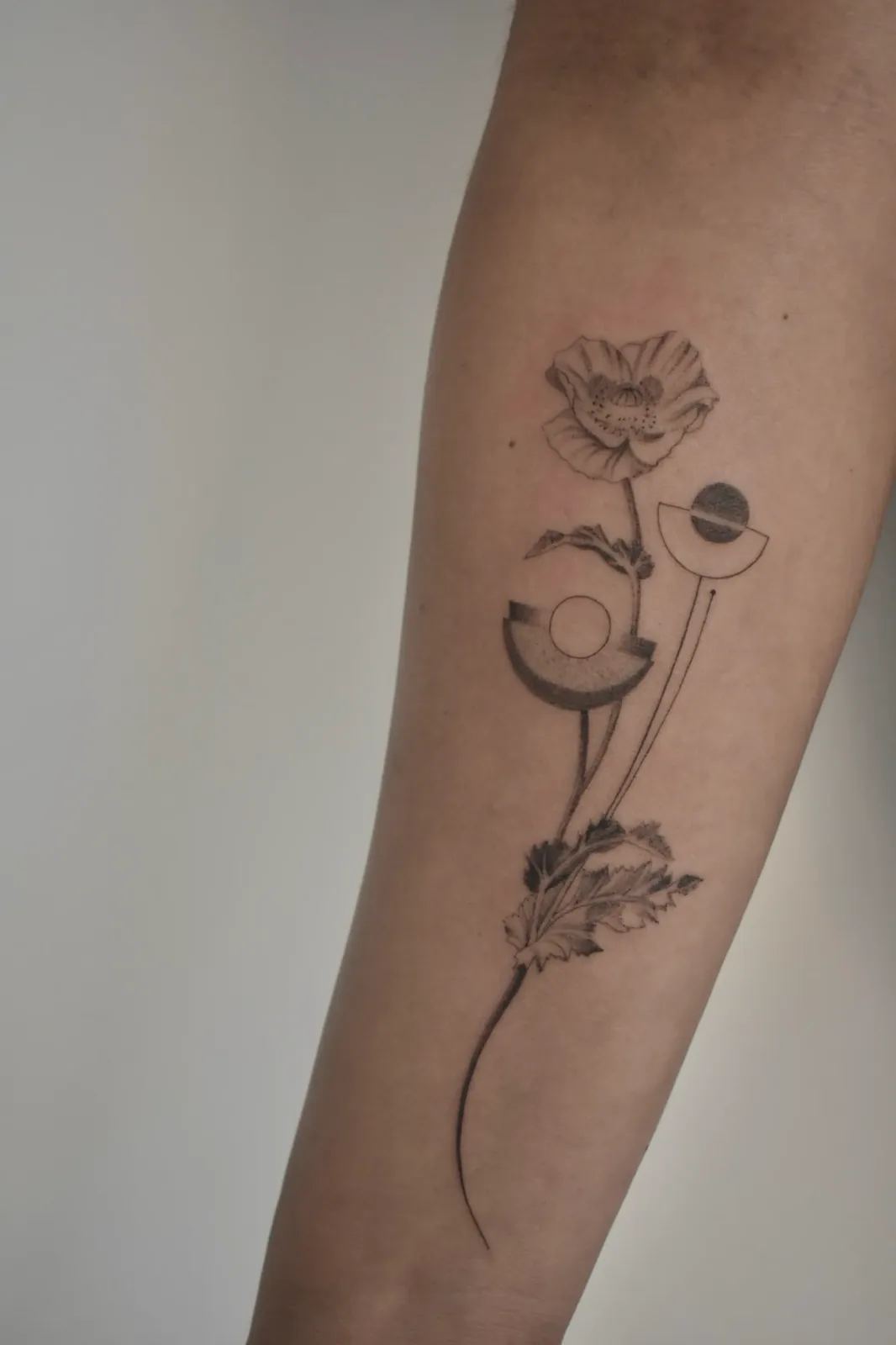 Fine-line poppy and geometric botanical tattoo on the forearm, GAR Tattoo