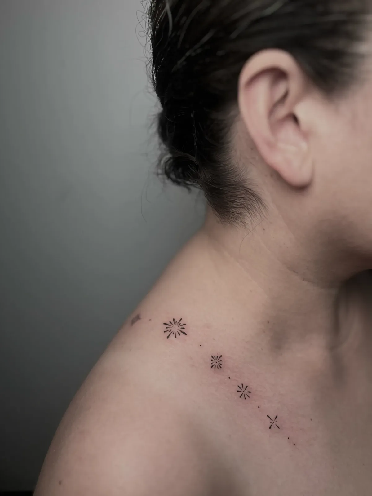 Delicate celestial fine-line pieces across the collarbone, healed, GAR Tattoo