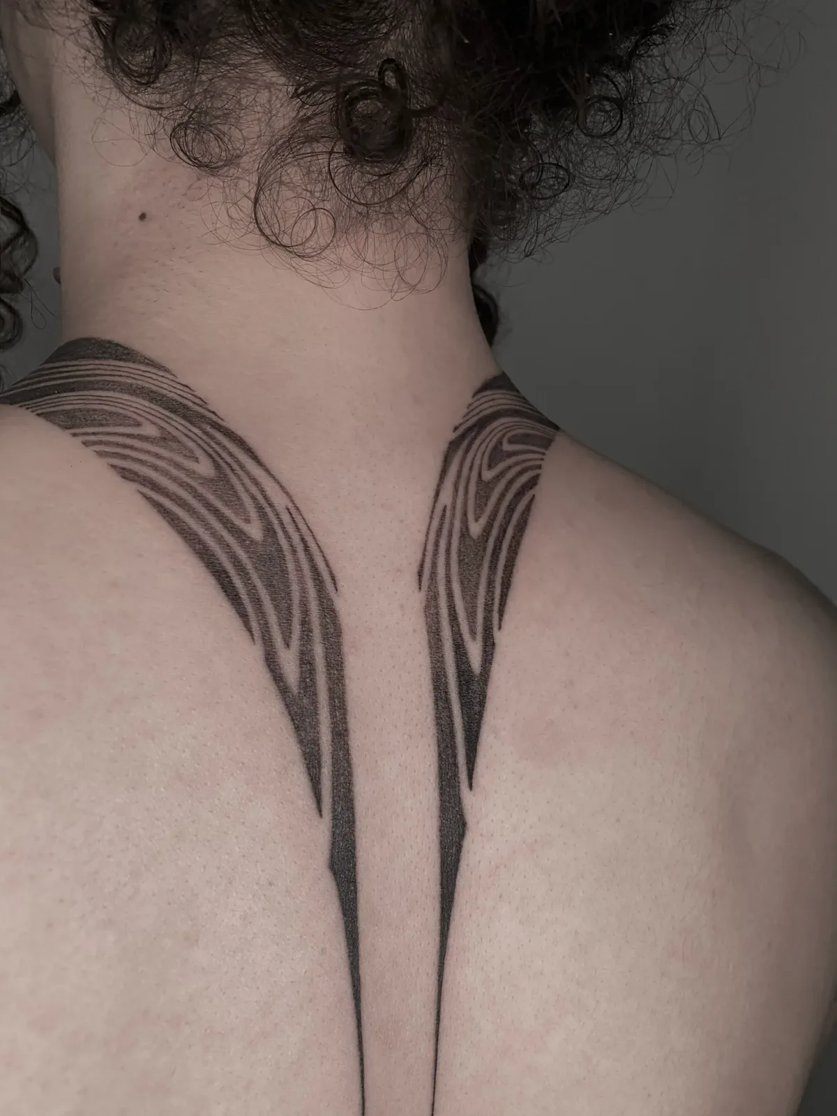 Symmetrical liquid fine-line flowing from the nape down the back, GAR Tattoo