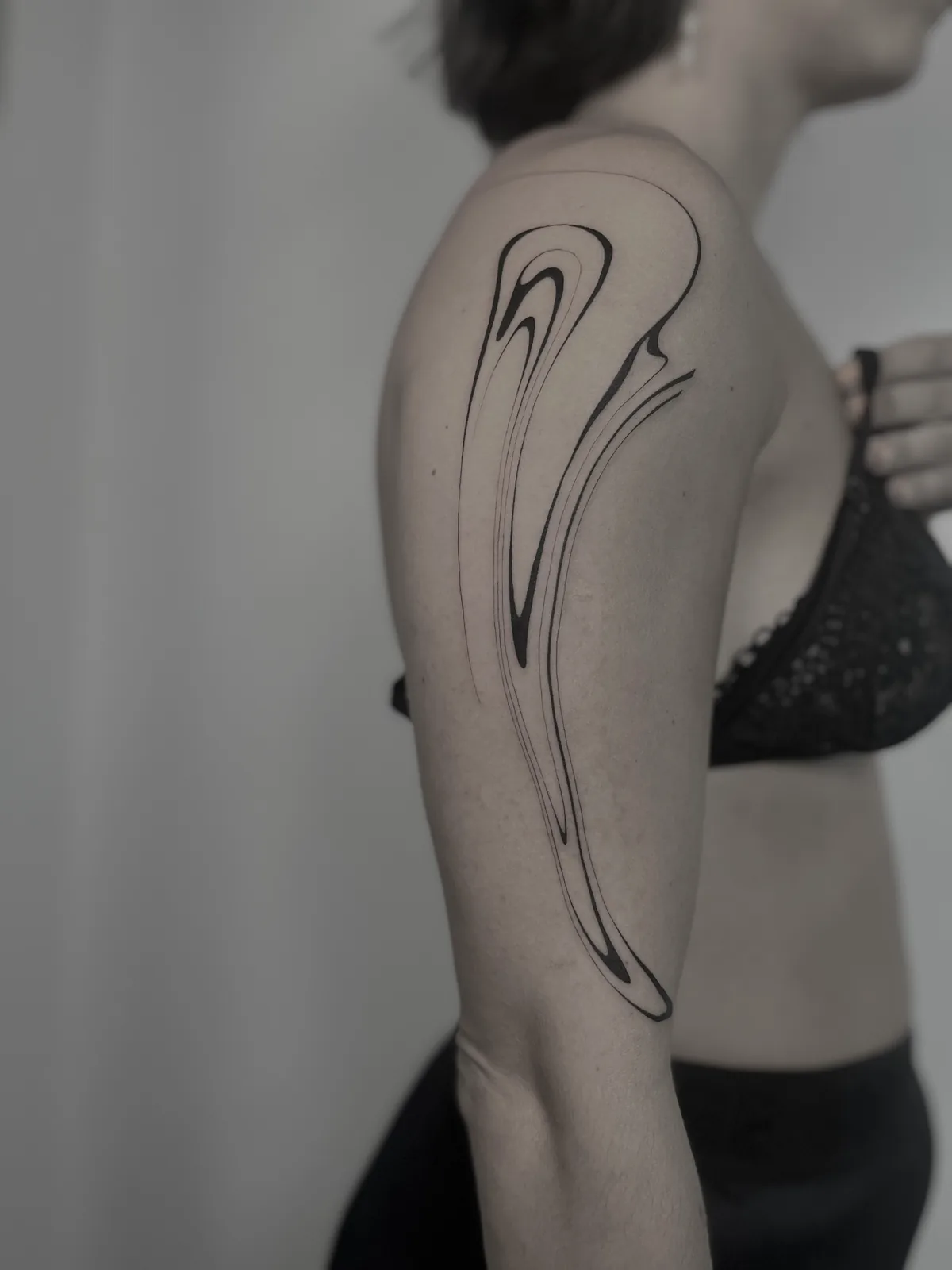 Liquid minimalist fine-line flame on the upper arm, GAR Tattoo